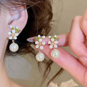 Close-up detail of French vintage enamel white flower earrings with hanging white pearls