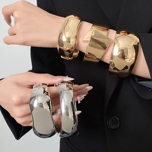 Close-up of model wearing chunky high-shine metallic bracelets in gold and silver