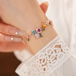 Close-up detail of a colorful zircon flower charm bracelet with 18k gold plating on a model