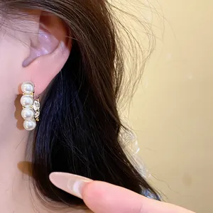 Detailansicht französischer Vintage-Creolen in Gold mit weißen Perlen und Strasssteinen.