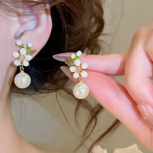 Detailed macro view of vintage enamel flower earrings featuring an elegant pearl drop