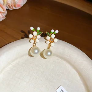 Detailed close-up of French retro enamel flower earrings with elegant hanging pearls.