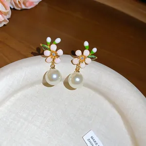 Close-up of enamel flower earrings with pearl drop in French retro style