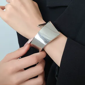Detailed view of high-shine silver geometric cuff bracelet worn with a black blazer