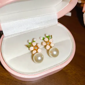 Close-up of elegant French vintage enamel flower earrings with large round white pearl drops