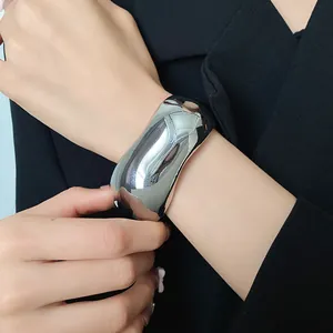 Close-up of a high-polish silver cuff bracelet worn with a black blazer for a chic look.