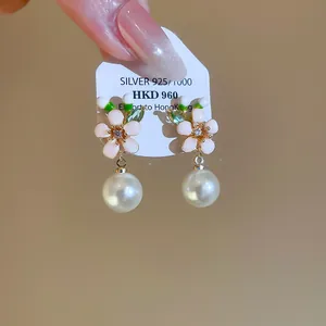 Close-up of elegant enamel flower earrings with white pearl drops in retro style.