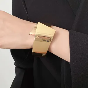 Macro view of a polished gold geometric cuff bracelet over a black sleeve
