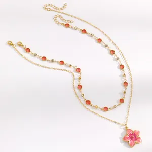Double layer gold necklace with pink enamel flower pendant and colorful crystal beads.