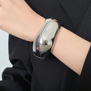 Macro detail of high-shine silver cuff bracelet featuring a minimalist organic shape