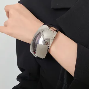 Macro view of wide polished silver cuff bracelet worn on wrist with black blazer
