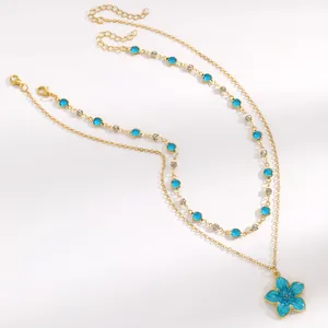 Double-layered gold chain necklace with blue crystals and an elegant blue flower pendant