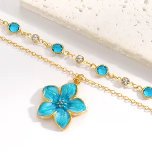 Close-up of blue enamel flower pendant and crystal embellished gold-tone chain necklace