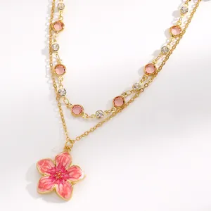Detailed close-up view of gold-tone layered necklace with pink enamel flower pendant
