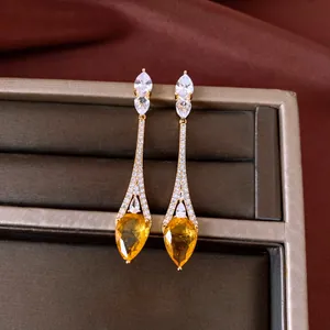 Detailed close-up of 18k gold plated drop earrings with pear-cut yellow zircons.