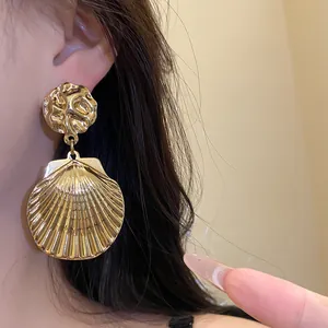 Detailansicht goldene Muschel-Ohrhänger mit Falten-Metallstruktur und Silbernadeln für Damen.