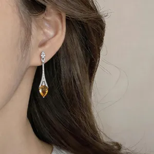 Detail shot of vintage 18k gold plated earrings with amber zircon teardrop on model's ear