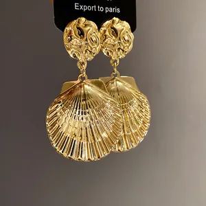 Detailansicht der goldenen Muschel-Ohrhänger mit eleganten, strukturierten Steckern