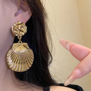 Nahaufnahme goldener Muschel-Ohrhänger mit einer elegant gefalteten Metalloberfläche