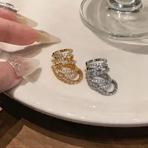 Close-up of gold and silver multi-layer zircon ear cuffs on a white ceramic plate