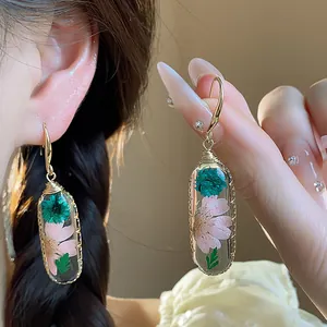 Orecchini ovali in resina con fiori secchi rosa e verde acqua e ganci dorati fatti a mano.