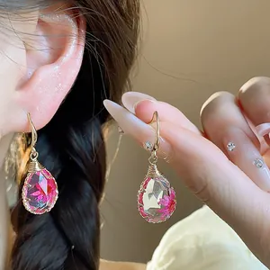 Dettaglio di orecchini a goccia in resina con fiori secchi rosa e ganci dorati chic
