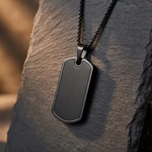 Minimalist black stainless steel dog tag necklace on a textured stone background.