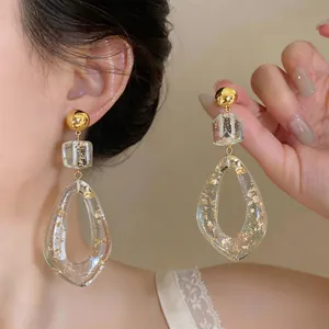 Close-up detail of elegant clear resin drop earrings with gold leaf inclusions on a model