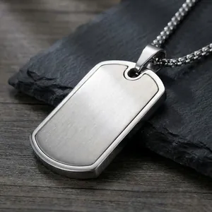 Brushed stainless steel dog tag necklace on a minimalist dark stone background