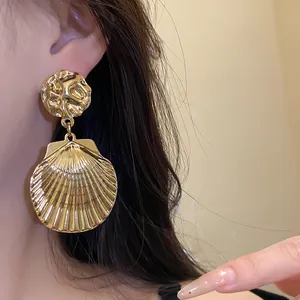 Detaillierte Nahaufnahme von eleganten goldfarbenen Muschel-Ohrhängern am Modell
