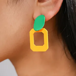 Dettaglio di orecchini geometrici dai colori vivaci a contrasto verde e giallo spruzzati
