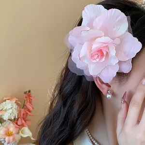 Elegante große Haarspange mit rosa Stoffblume aus Mesh im Detail am Haar eines Models