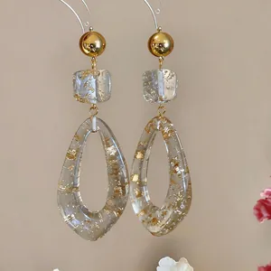 Detailed view of elegant resin drop earrings with gold foil inclusions on light background