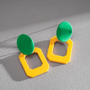 Dettaglio di orecchini geometrici moderni in colori contrastanti verde e giallo