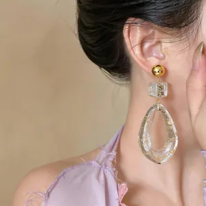 Close-up detail of irregular resin drop earrings with gold flakes worn by model