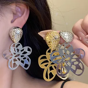 Detailansicht großer hohler Blumenanhänger-Ohrringe mit metallischer Textur