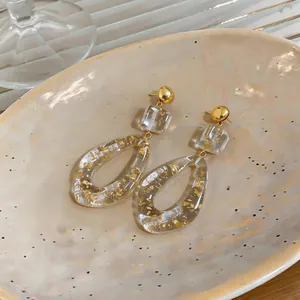 Macro detail of resin drop earrings with elegant gold foil flakes and minimalist design