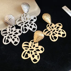 Detailansicht von hohlen Blumenanhänger-Ohrringen in Gold- und Silberfarben. Chic.
