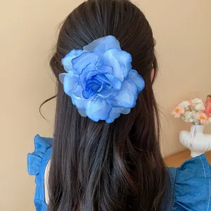 Eleganter Haarclip mit blauer Stoffblume aus Netzstoff auf langem dunklem gewelltem Haar