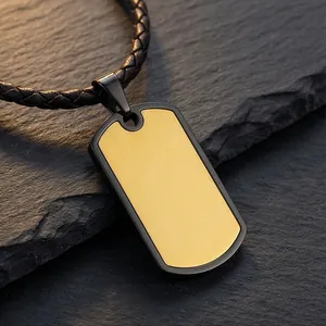 Close-up detail of a brushed gold and black stainless steel dog tag pendant on a braided cord