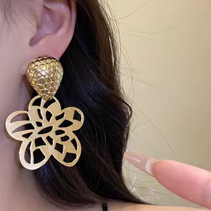 Detaillierte Nahaufnahme von goldenen Ohrhänger in Blumenform im Vintage-Stil am Model