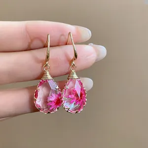 Dettaglio di eleganti orecchini a goccia in resina con veri fiori secchi rosa fatti a mano