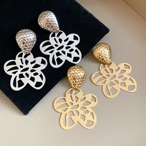 Detailansicht der exquisiten gold- und silberfarbenen Hohlblumen-Ohrhänger mit Textur
