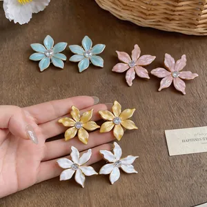 Close-up of 18k gold plated enamel flower stud earrings with zircon in various soft colors.
