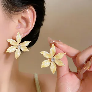 Close-up of elegant cream enamel flower stud earrings with a central sparkling zircon stone.
