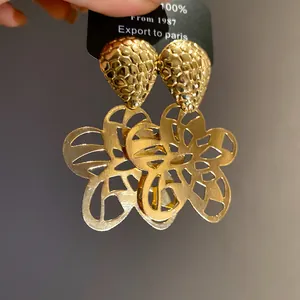 Nahaufnahme goldener hohler Blumen-Ohrhänger im Retro-Stil mit Textur