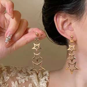 Close-up of gold-plated stainless steel dangling star earrings with four hollow stars.