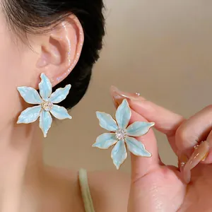 Detailed close-up of light blue enamel flower stud earrings with a clear zircon center