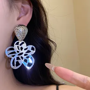 Detaillierte Nahaufnahme von Vintage-Ohrringen mit hohler Blumenform aus glänzendem Metall