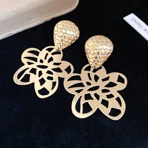 Nahaufnahme eleganter goldfarbener Hohlblumen-Ohrringe mit einem Oberteil in Wabenstruktur